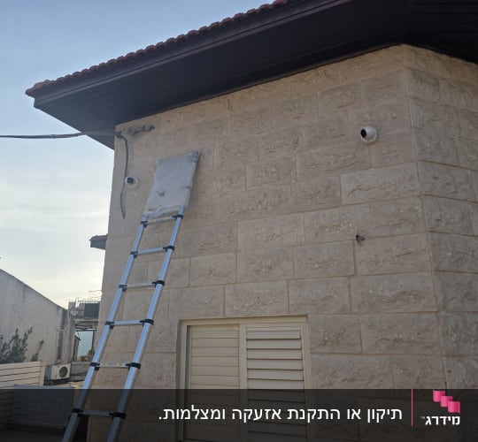 סולם ליד קיר עם מצלמות אבטחה מותקנות